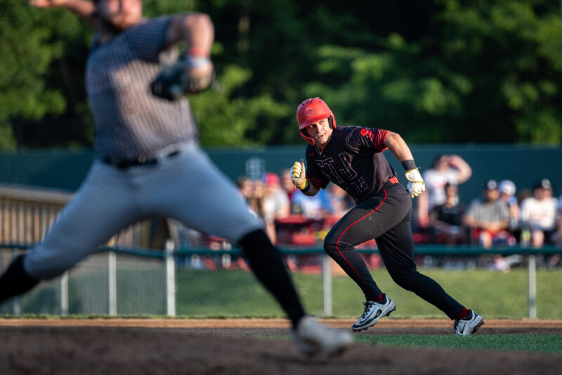 A St. Joseph Mustangs player steals second as the pitcher unwinds on the mound.